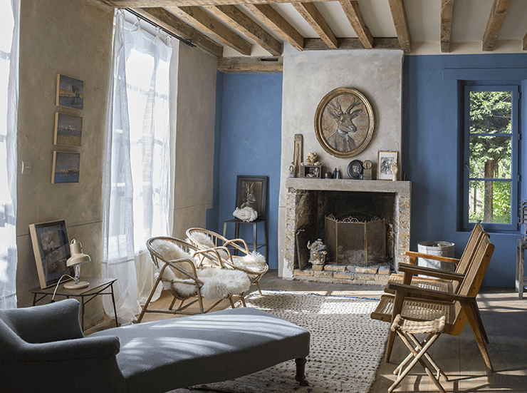 Salon avec mur bleu, canapé et chaises dans une maison de normandie