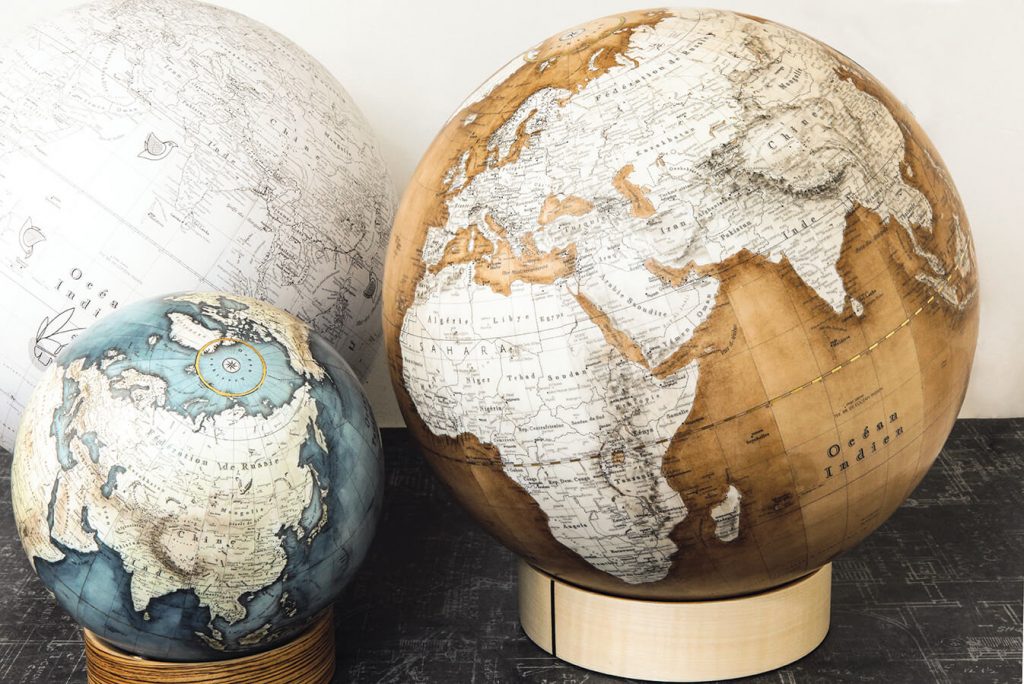des globes terrestres de petite taille est positionné devant deux autres globes plus grands