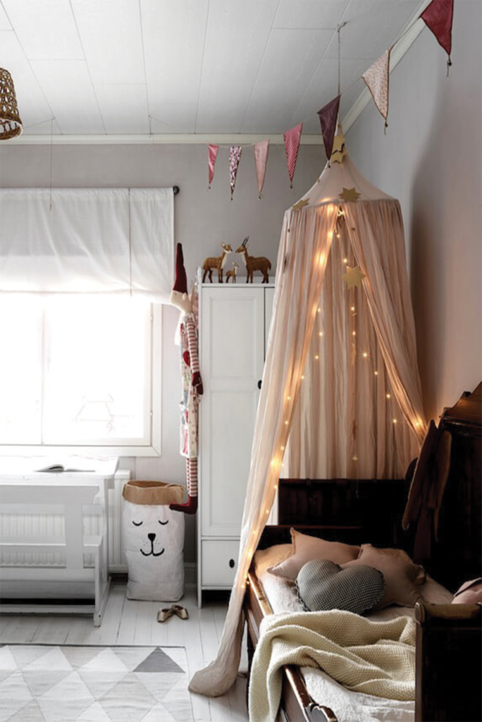 Chambre enfants avec un baldaquin décoré de guirlandes
