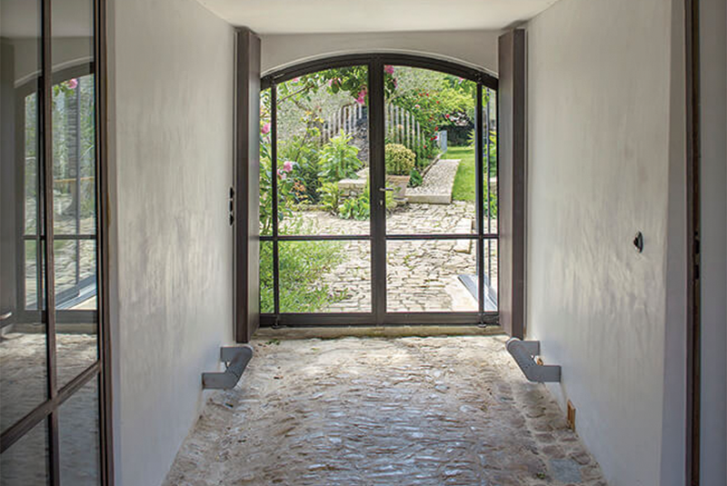 Couloir d'entrée avec pierre au sol et porte d'entrée en verre