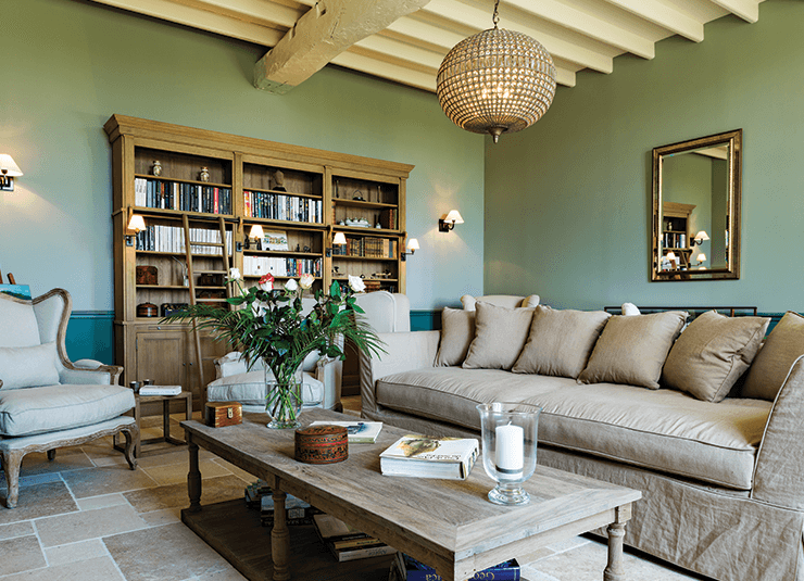 salon avec mur vert et canapé gris accompagné d'une table en bois