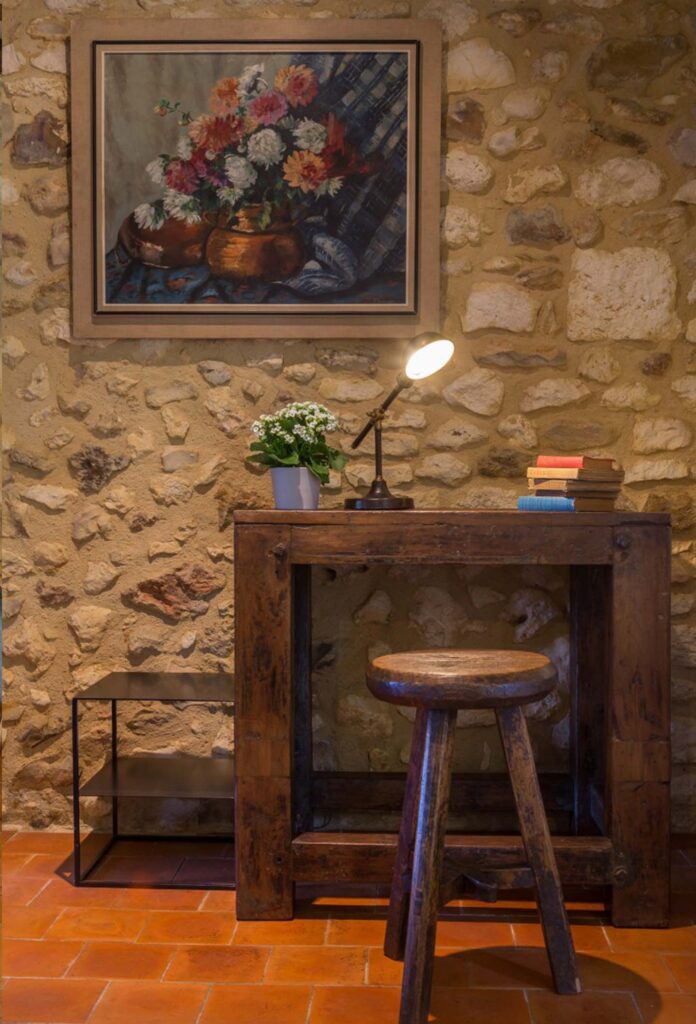 mur en pierre avec table en bois et tabouret en bois
