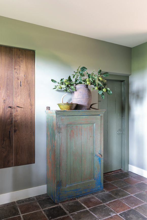 La porte a été peinte dans la même teinte de vert sauge que le placard de la cuisine. Cette couleur se marie très bien avec le carrelage ancien.