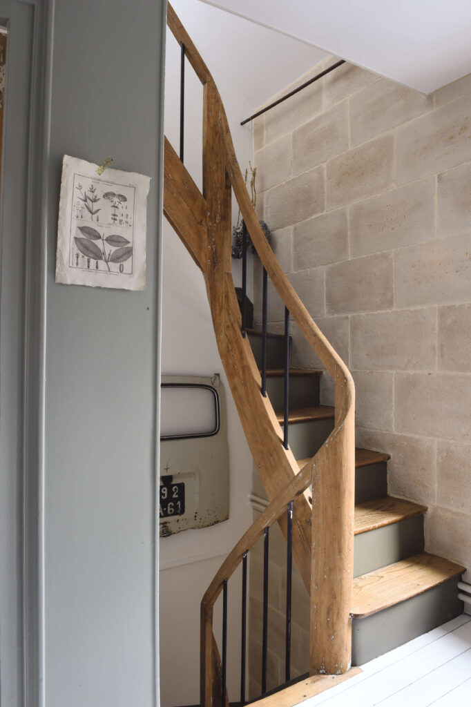 Dans la monté d’escalier, Stéphanie a accroché une porte arrière de 4L chinée (Chez Nous Campagne). Les contremarches de l’escalier sont peintes en kaki.