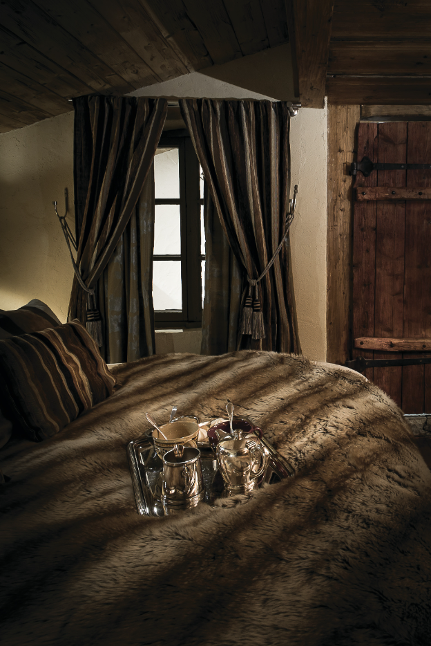 Une des suites d’hôtes du chalet de montagne décorée dans une ambiance cocooning avec un plaid en fausse fourrure pour un esprit nid douillet.