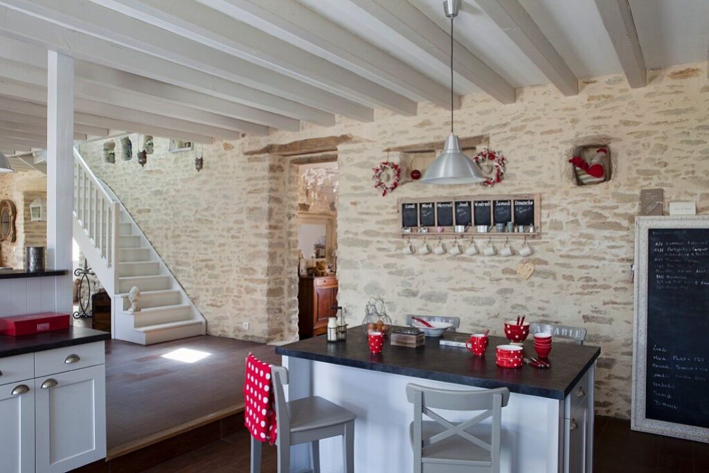 Comptoir pour le petit-déjeuner dans une cuisine ouverte avec un plafond à poutres en bois gris et blanc et un mur en pierre naturelle