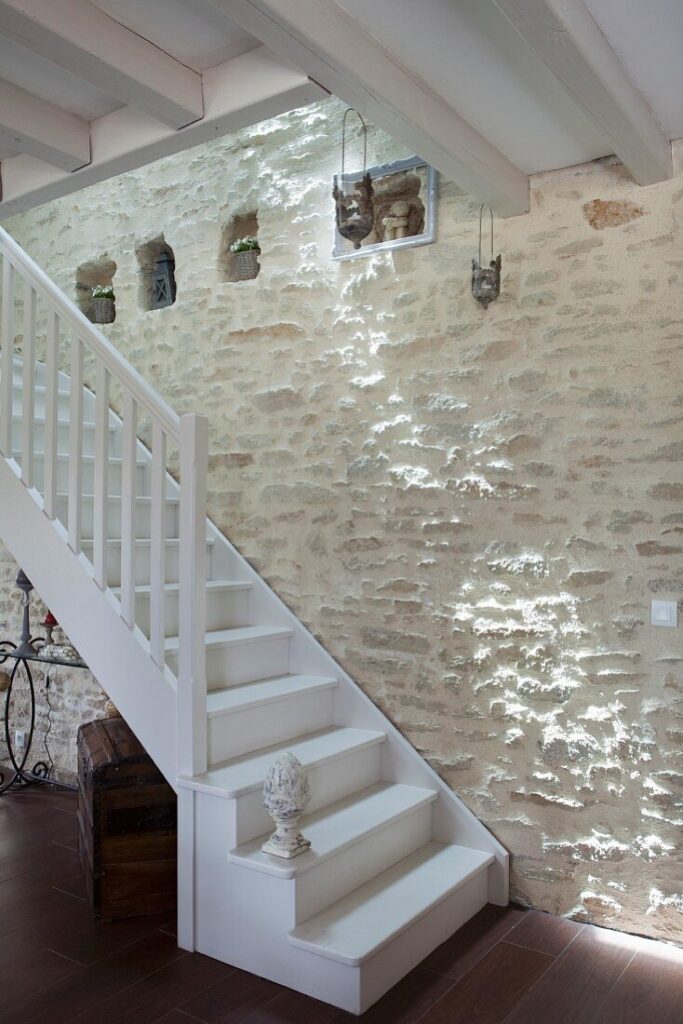 L’escalier peint en blanc comme le plafond du séjour permet d’accéder à l’étage des chambres lovées sous les combles.