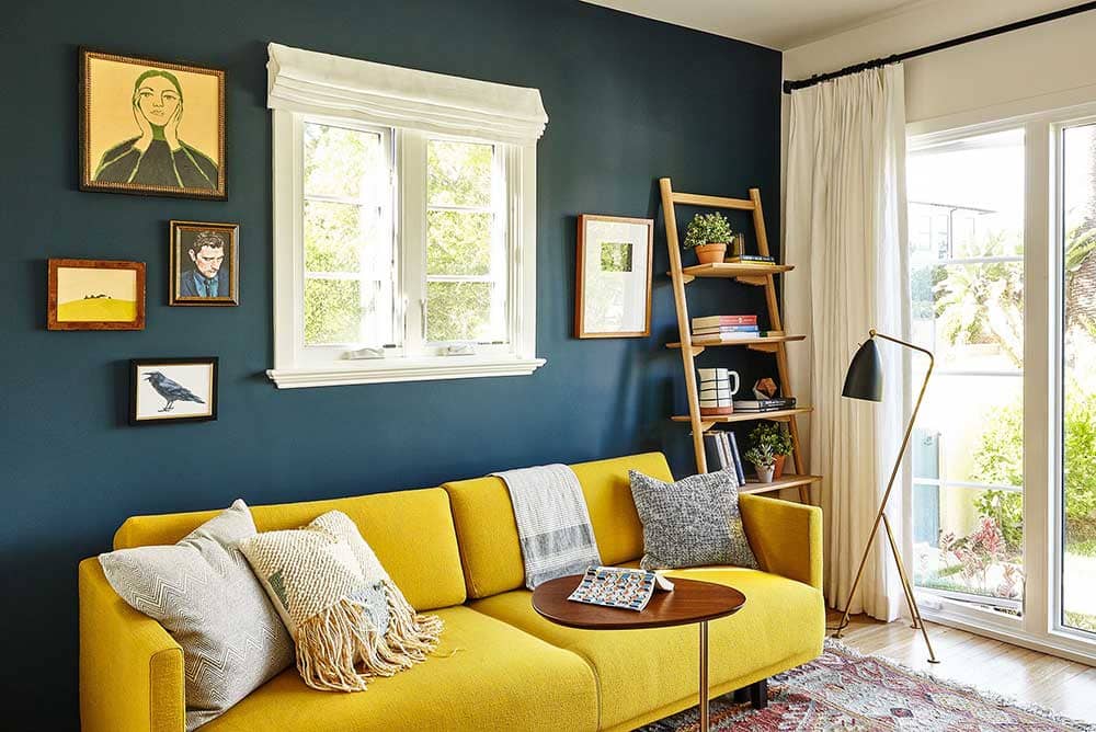 salon avec canapé jaune et mur bleu pétrole